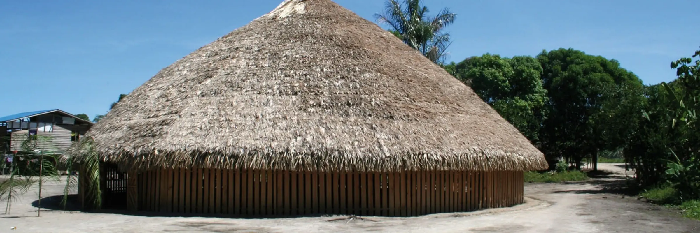 ein runes Versammlungshaus aus Holz mit Strohdach