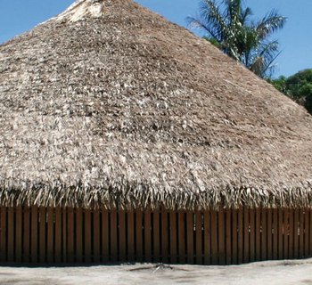 ein runes Versammlungshaus aus Holz mit Strohdach